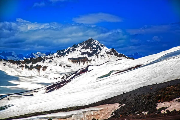 Neve nas montanhas contra o céu azul nas nuvens.A região do Elbrus.O Cáucaso . — Fotografia de Stock