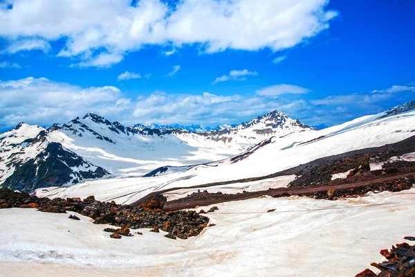 Neve nas montanhas contra o céu azul nas nuvens.A região do Elbrus.O Cáucaso . — Fotografia de Stock