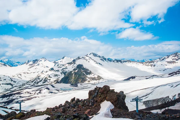 Neve nas montanhas contra o céu azul nas nuvens.A região do Elbrus.O Cáucaso . — Fotografia de Stock