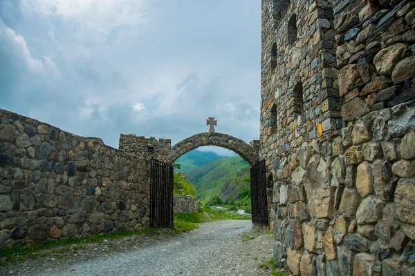 Klasztor z kamienia, stary kościół w górach. Kamienne wejście do świątyni, łuk z krzyżem na szczycie. Caucasus.Russia. — Zdjęcie stockowe