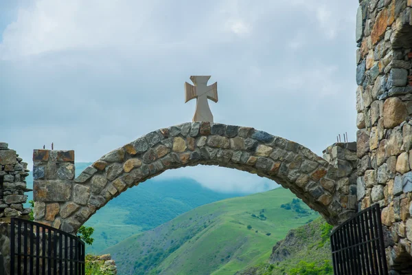 Klasztor z kamienia, stary kościół w górach. Kamienne wejście do świątyni, łuk z krzyżem na szczycie. Caucasus.Russia. — Zdjęcie stockowe