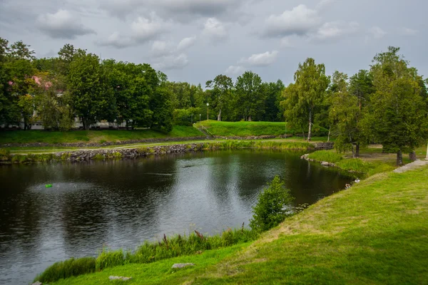 Prachtig meer en bomen weerspiegeld water. Zomer, hemel met wolken, bewolkt weer. Rusland, de stad van Priozersk. — Stockfoto