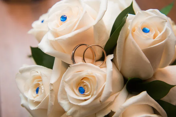 Twee trouwringen liggen op een boeket van witte rozen — Stockfoto