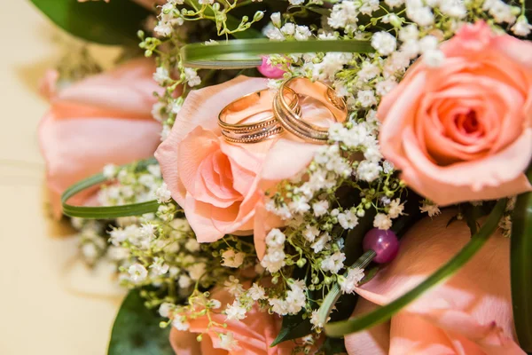 Twee trouwringen op een boeket van roze rozen — Stockfoto