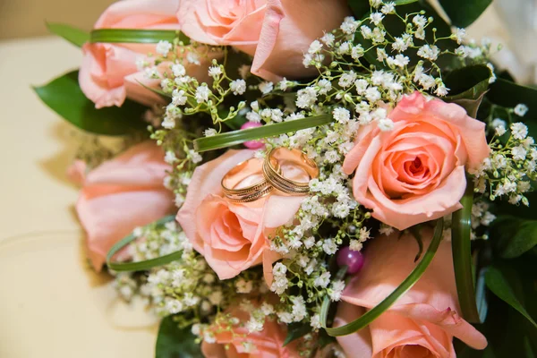 Dois anéis de casamento em um buquê de rosas rosa — Fotografia de Stock