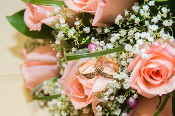 Dois anéis de casamento em um buquê de rosas rosa — Fotografia de Stock