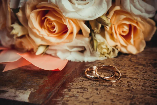 Twee trouwringen en een boeket van Oranje en witte rozen. — Stockfoto