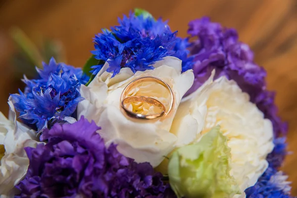 두 개의 결혼 반지와 파란색, 흰색, 보라색 꽃의 꽃다발. — 스톡 사진