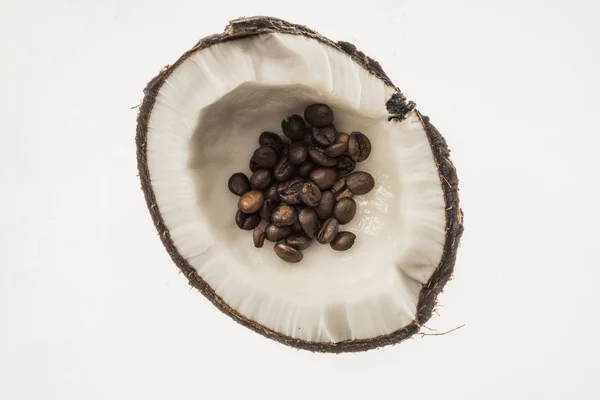 Chicchi di caffè tostati in cocco fresco, isolati su bianco Foto Stock