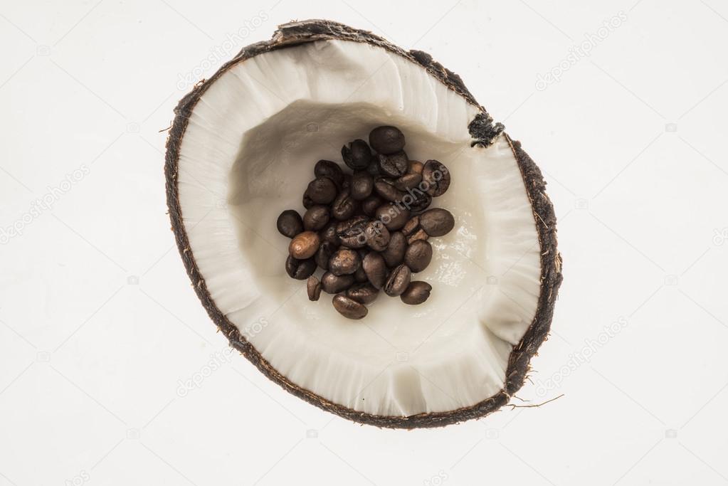 Roasted coffee beans in fresh coconut, isolated on white