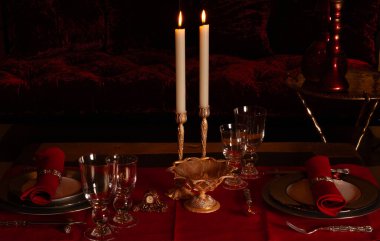 Kandilli kırmızı kadife masa ve bir kadeh şarap.