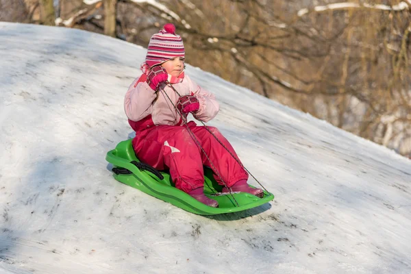 Bir yokuş aşağı sürme kızak üzerinde küçük kız