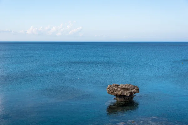 Roca solitaria en medio del mar azul — Foto de Stock