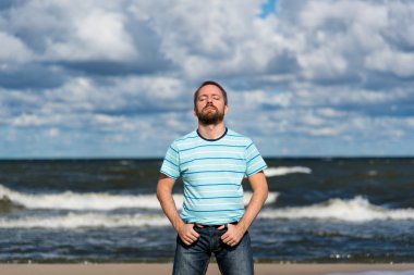 Genç adam bir kumsalda düşünürken