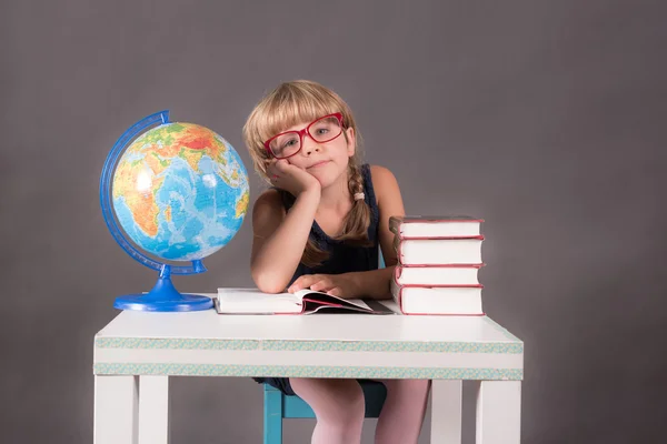 Kitap bir masada yaslanmış büyük kırmızı gözlük takan kız öğrenci