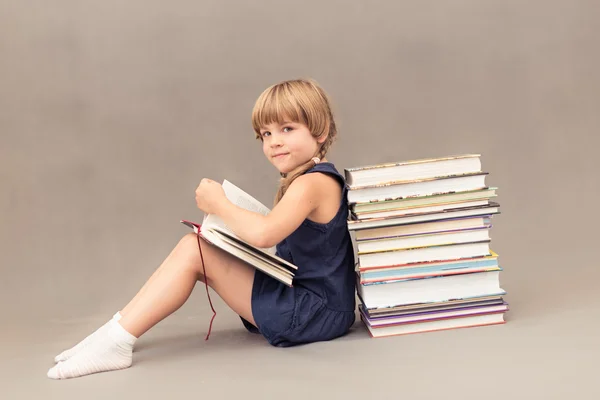 Iskolás támaszkodva a verem a könyvek és az olvasás — Stock Fotó