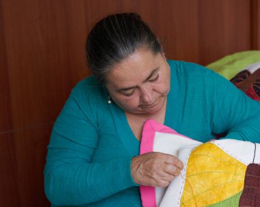 Latin kadın elle dikiş dikiyor yorgan ve yatak örtüleri dikiyor..                                 