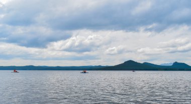 İnsanlar kayıkla geziyor. Büyük güzel bir göl. Ufuktaki güzel dağlar Fırtına Bulutları. Kazakistan 'ın doğasının güzel manzarası. Burabay, Kazakistan.