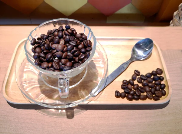 Pile Brown Roasted Coffee Beans Transparent Coffee Cup Spill Wooden — Stock Photo, Image