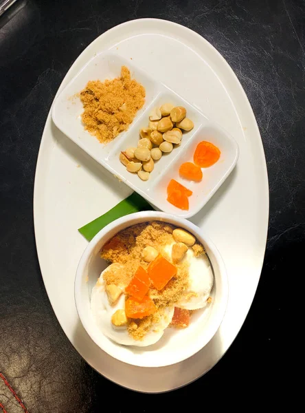 Taze hindistan cevizi sütlü dondurma üzerine kızarmış domuz ipi, yer fıstığı, siyah arka planda tuzlu yumurta..