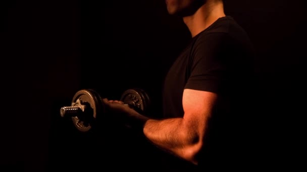 Muscular bodybuilder doing dumbbell curls on a black background — Stock Video