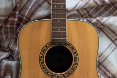 Karadelik ve kahverengi desenli telleri olmayan hafif ahşap gitar ve yün kahverengi kareli ekose.