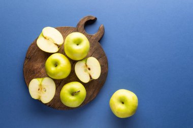 Taze yeşil elmalar mavi bir arka planda doğrama tahtasında