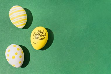 Yeşil zemin üzerinde renkli paskalya yumurtaları sert açık siyah gölgeler sert gölgeler