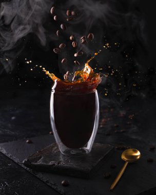 Sıcak espresso sabah kahvesi, cam bardakta. Kokulu içecek üzerine kahve çekirdekleri ve siyah arka planda buhar dökülüyor. Pankart tasarımı