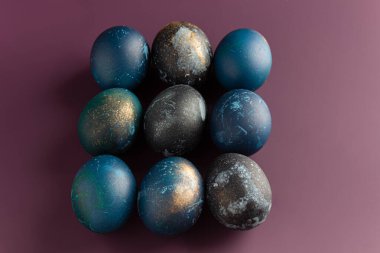 Mor arka planda güzel çiçekleri olan boyalı paskalya yumurtaları. Desen