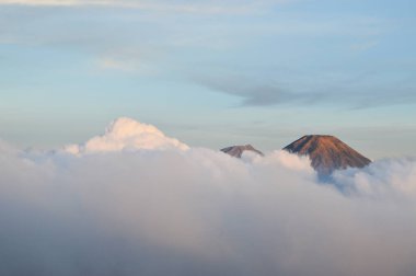 Bulutların arkasında iki dağ zirvesi görünüyor.