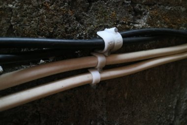 Beton duvara çivilenmiş siyah ve beyaz kablolar.