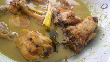 Yumuşak tavuk parçaları, baharatlı ve şifalı bitkilerle dolu sarı et suyunda kaynıyor.