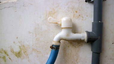 Duvara bağlı mavi hortumlu açık deniz musluğu..