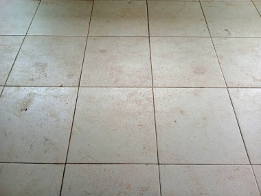 Kirli açık gri seramik döşeme, harç çizgileri, lekeler, sürtünmeler ve toz ile temizleme veya yenileme kavramları için arka plan dokusu.