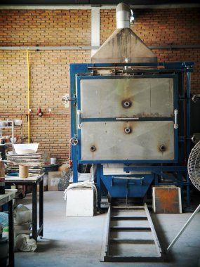 Bir tasarım okulu atölyesinde öğrenci ve proje deneyi için kullanılan çağdaş metal endüstriyel seramik fırının ön tarafı kapalı.      