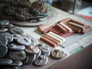 Bir endüstriyel tasarım okulunun bir gösteri fabrikası atölyesinde öğrenciler tarafından yapılan seramik üretim süreci eğitimi için örnek parçalarla birlikte egzersiz masası 