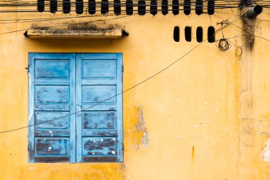 old yellow house facade in vietnam with a blue window