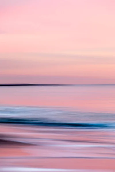 Abstrakte Landschaft des Meeres. Textur Wasser, Himmel und Sand in verschwommener Bewegung in tropischen Sonnenuntergangsfarben — Stockfoto