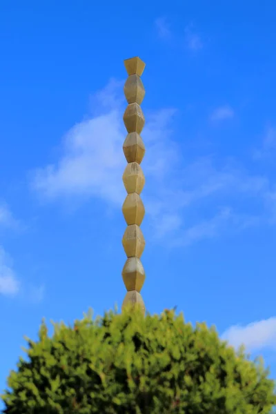 Targu Jiu, RO - 7 Kasım 2020: Constantin Brancusi Heykeller Topluluğundan Sonsuz Sütun. 1. Dünya Savaşı 'nın Romen kahramanlarına hürmet. Yeşil bitki örtüsü ve mavi gökyüzü ile sanatsal bakış açısı. UNESCO dünya mirası anıtı. Modernizm heykeli.