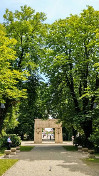 Targu Jiu, RO - 20 Haziran 2020: Öpücük Kapısı (Poarta Sarutului) Constantin Brancusi Heykel Topluluğu 'ndan. Birinci Dünya Savaşı 'nın Romen kahramanlarına hürmet. Sandalyeler Sokağı 'ndan renkli bir yaz manzarası. UNESCO Anıt Alanı