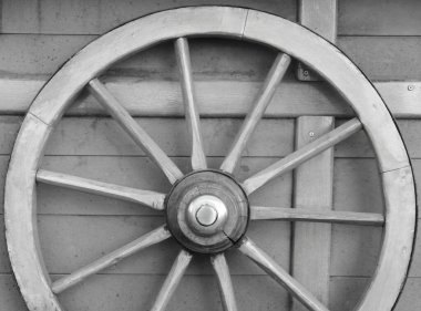 Ahşap arka plan monokrom fotoğraflı eski ahşap bir araba tekerleği. Rustik temalı görüntü. Kırsal dekoratif öge.