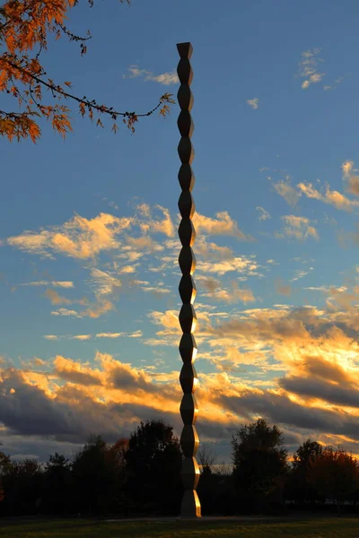 Targu Jiu, Romanya - 31 Ekim 2020: Constantin Brancusi Heykel Topluluğundan Sonsuz Sütun (Coloana Infinitului). Birinci Dünya Savaşı 'nın Romen kahramanlarına hürmet. Sanatsal altın renkli günbatımı ışığı.