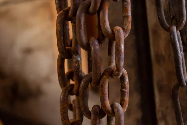 rusty chain hanging in a barn, heavy chain, large, old chain ,iron rusty chain