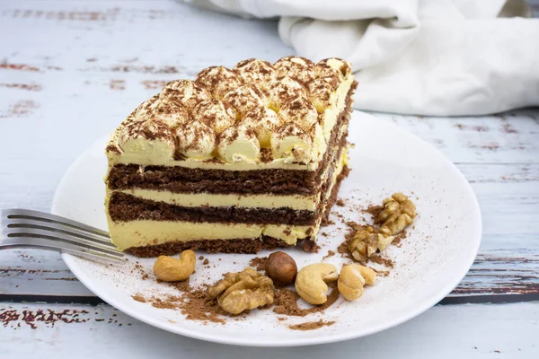 sweet nut dessert, chocolate puff cake, tiramisu, striped honey cake, a piece of cream cake on a white plate with nuts