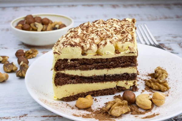 sweet nut dessert, chocolate puff cake, tiramisu, striped honey cake, a piece of cream cake on a white plate with nuts