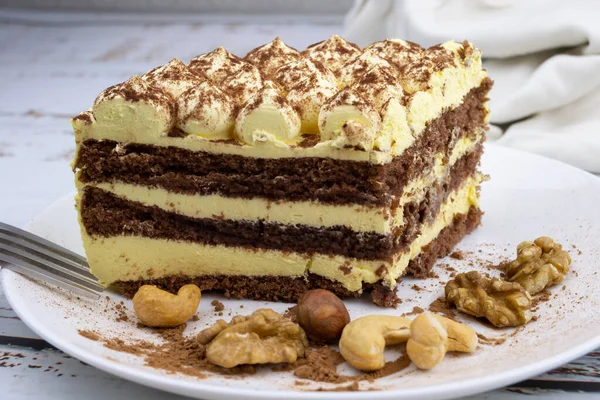 sweet nut dessert, chocolate puff cake, tiramisu, striped honey cake, a piece of cream cake on a white plate with nuts