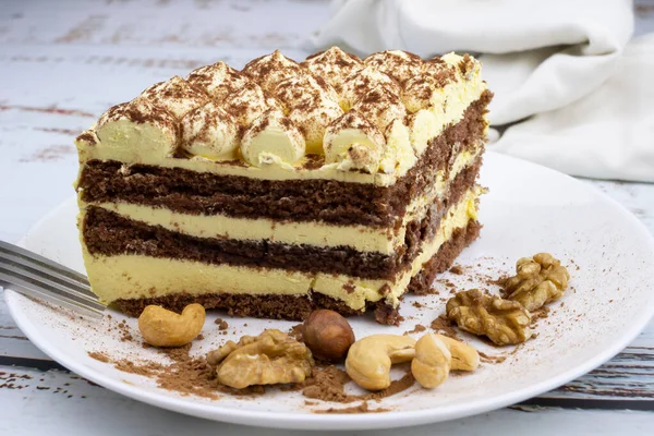 sweet nut dessert, chocolate puff cake, tiramisu, striped honey cake, a piece of cream cake on a white plate with nuts