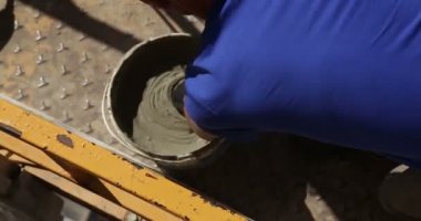 İnşaat. Adam harç kova mala ile alır.