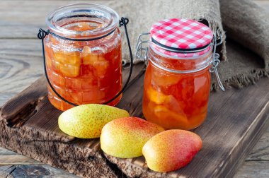 Ahşap masada ev yapımı armut reçeli ve taze olgun armutlar..